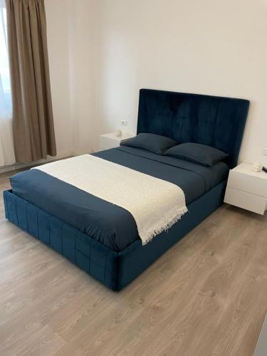ein blaues Bett in einem Schlafzimmer mit Holzboden in der Unterkunft Luna Luxury Apartment by the Zoo in Râmnicu Vâlcea