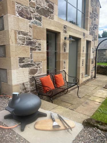 a bench with two orange pillows and a hat at Woodmill Arches - Designer Barn Conversion for Two in Lindores