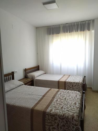 a bedroom with two beds and a window with curtains at Apartamento con vistas al mar y buena ubicación in Benicàssim