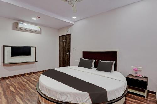 a bedroom with a large bed and a flat screen tv at Collection O Hotel Royal Inn in Ahmedabad