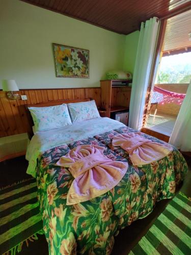 a bedroom with a bed with a floral bedspread at Pousada Solar das Flores Maringá RJ Visconde de Mauá in Visconde De Maua
