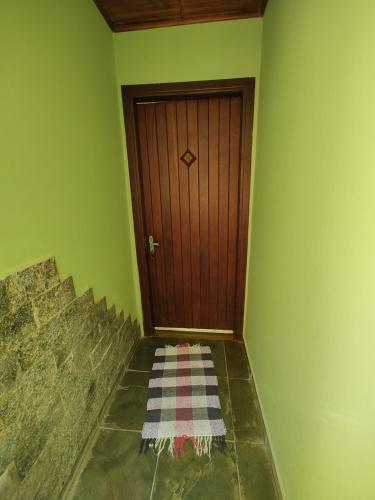 a hallway with a wooden door and a rug on the floor at Pousada Solar das Flores Maringá RJ Visconde de Mauá in Visconde De Maua