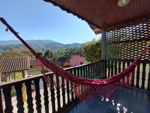 a hammock on a balcony with mountains in the background at Pousada Solar das Flores Maringá RJ Visconde de Mauá in Visconde De Maua