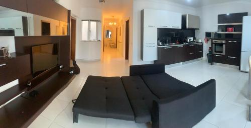 salon z czarną kanapą i kuchnią w obiekcie St Pauls Bay Luxury 2 bedroom Apartment Blue Water Suite Flat 36 w mieście St Paul's Bay