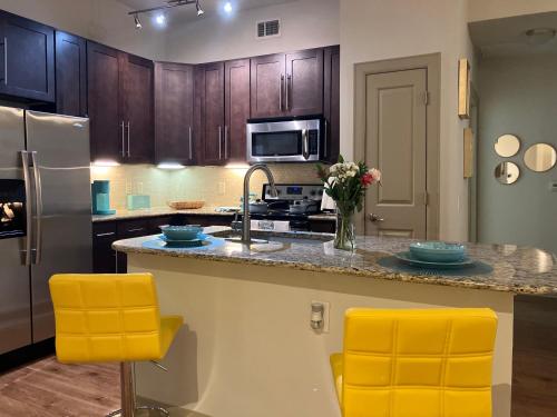 a kitchen with a sink and two yellow bar stools at Heart of NRG and Medical Center in Houston