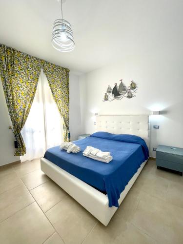 um quarto com uma cama com lençóis azuis e uma janela em B&B Marconi em Ricadi