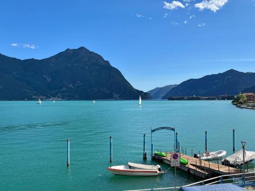 a dock with two boats on a lake with mountains at Hotel Lovere Resort & Spa in Lovere