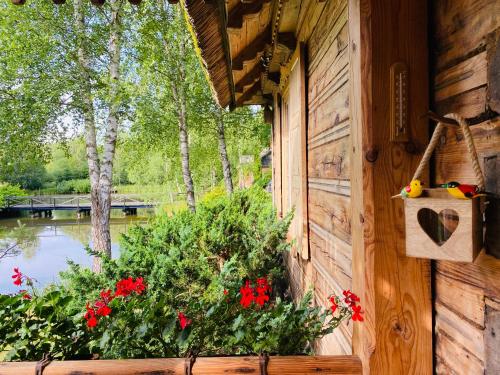 - une fenêtre d'une maison en bois ornée de fleurs et offrant une vue sur le lac dans l'établissement Koronkowa Chata, à Michalin