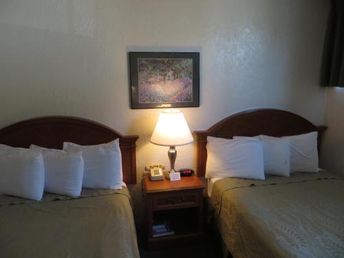 a hotel room with two beds and a lamp on a table at Americas Best Value Inn Loma Lodge in San Diego