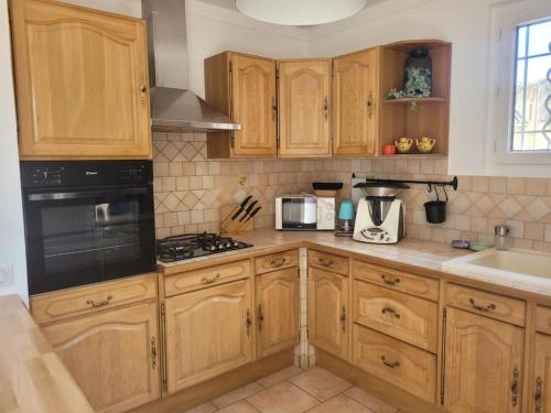 une cuisine avec des armoires en bois et un four à plaques de cuisson dans l'établissement Maison 6-8 pers au cœur du village, à Malaucène