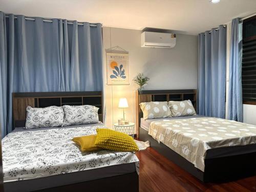 2 Betten in einem Schlafzimmer mit blauen Vorhängen in der Unterkunft Sukhumvit villa/花園私密獨棟5房/輕軌步行3分鐘/預定3天送接機服務 in Amphoe Phra Khanong