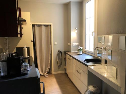 uma pequena cozinha com um lavatório e uma janela em Appartement Périgueux historique em Périgueux
