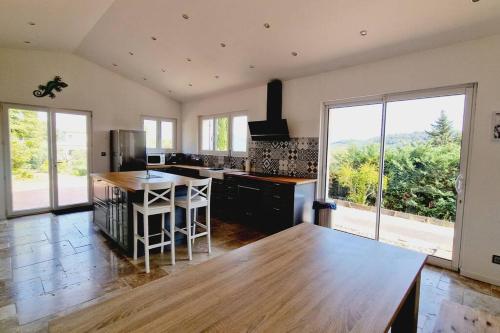 uma cozinha com uma mesa de madeira e uma grande janela em Aux trois Cyprès Salernes en Provence em Salernes