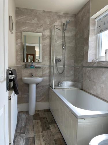 a bathroom with a tub and a sink and a shower at The Downs, Thurlestone, South Devon, close to several beaches in Kingsbridge