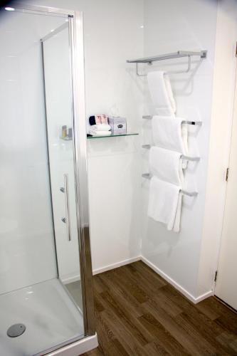 a bathroom with a shower and white towels at Camelot On Ulster in Hamilton