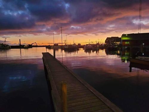 een jachthaven bij zonsondergang met boten in het water bij Det Gamle Garnbinderi, ved Møns bedste strand. in Borre