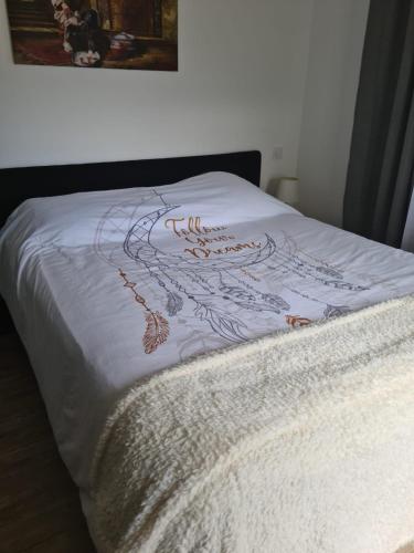 Una cama con una manta blanca con un diseño. en Cherad, en Arveyres