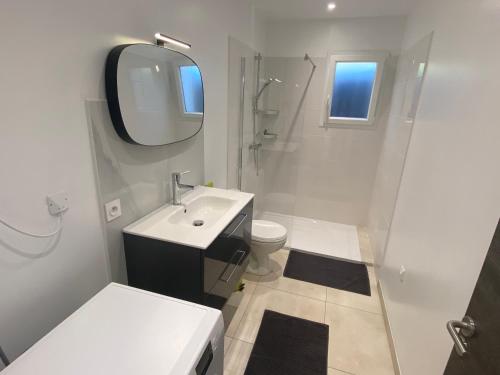 uma casa de banho branca com um lavatório e um espelho em JOLIE MAISON A 700M DE LA MER em Le Grau-dʼAgde