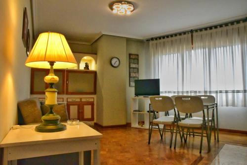 ein Wohnzimmer mit einem Tisch mit Stühlen und einer Lampe in der Unterkunft Puerta la Villa in Avilés