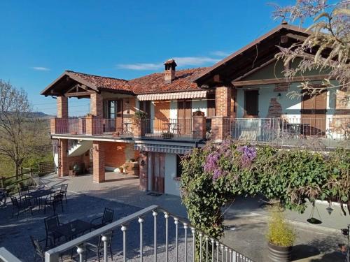 a brick house with a balcony and tables and chairs at Agriturismo Bric di Gai in Monforte dʼAlba
