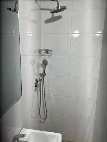 a white bathroom with a shower and a sink at Westlands Tower - Ghana Villas in Accra