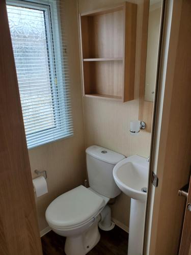 a small bathroom with a toilet and a sink at your happy place in Rhyl