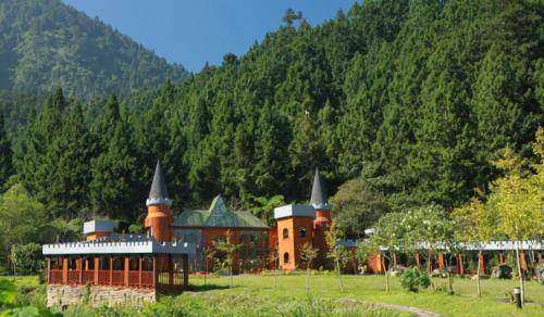a building with two towers on a field with a mountain at 晨煦行旅 in Lugu