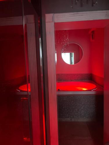 a red bathroom with a red tub and a mirror at L’ Aia del Principe in Montepulciano