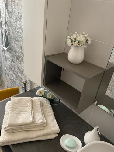 a bathroom with a table with a vase of flowers at B&B Da Leone in Palazzolo dello Stella