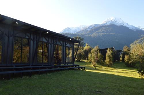 a building in a field with mountains in the background at Base Puelo in Cochamó