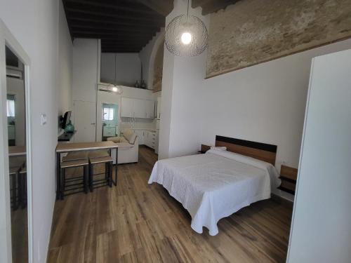 a bedroom with a bed and a table and a kitchen at Apartamento El Arrumbador in Jerez de la Frontera