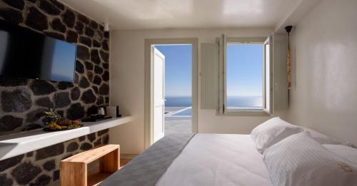 a bedroom with a bed with a view of the ocean at Terra Blanca Suites in Imerovigli