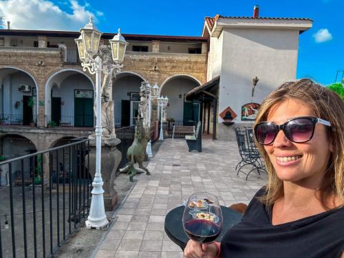 a woman is holding a glass of wine at Palazzo Capece in Caivano