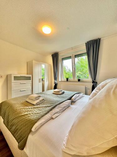a bedroom with a large bed and two windows at Großes City-Ferienhaus mit Terrasse, Grill und Parkplatz F19 in Oldenburg