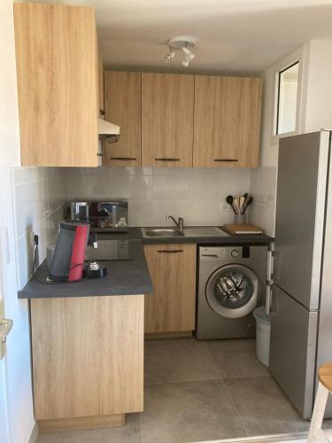 - une cuisine avec des placards en bois et un lave-linge dans l'établissement F2 Pompeani, à Ajaccio