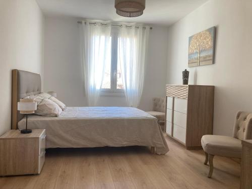 a bedroom with a bed and a chair and a window at F2 Pompeani in Ajaccio