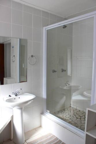 a white bathroom with a sink and a shower at Hysie oppie see in Jongensfontein