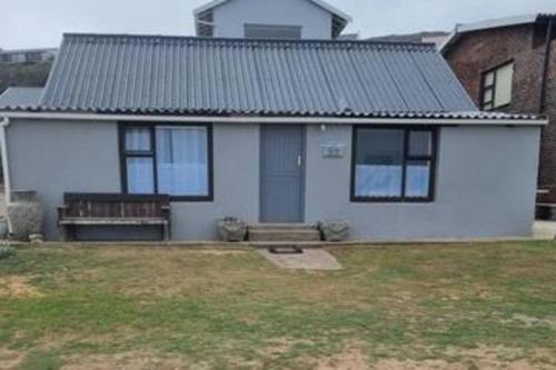 a white house with a bench in a yard at Hysie oppie see in Jongensfontein