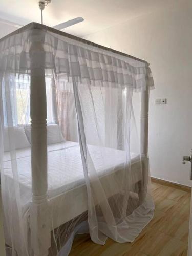 a bed with a canopy in a room at JiPende Penthouse in Kilifi