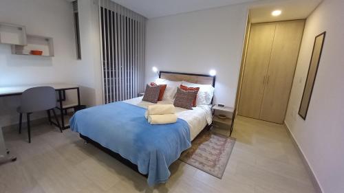 - une chambre avec un lit doté d'une couverture bleue et d'un bureau dans l'établissement Apartaestudio San Martin, La Quinta, à Bogotá