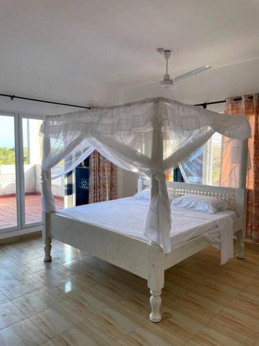 a white bed with a canopy in a room at JiPende Penthouse in Kilifi