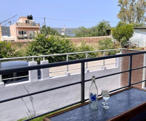 a table with two glasses and a bottle on a balcony at Souda Bay in Souda