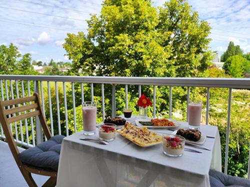 einen weißen Tisch mit Speisen und Getränken auf dem Balkon in der Unterkunft Appartement avec deux balcons in Magny-les-Hameaux