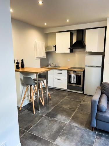 une cuisine avec des armoires blanches et une table en bois dans l'établissement Charmant Appartement au Cœur de Blois, à Blois