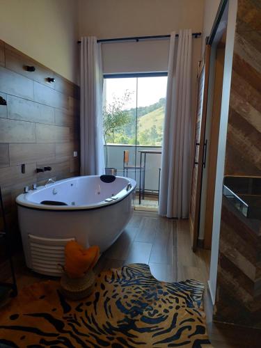 uma casa de banho com uma banheira grande e uma janela grande em Toca Hospedaria - Centro em São Bento do Sapucaí