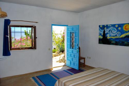 a bedroom with a blue door and a window at Cortijo Los Maximos in Turón