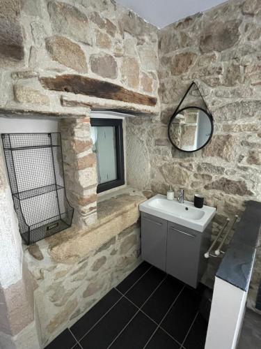 uma casa de banho em pedra com um lavatório e um espelho em Gîte La Morille em Ravel