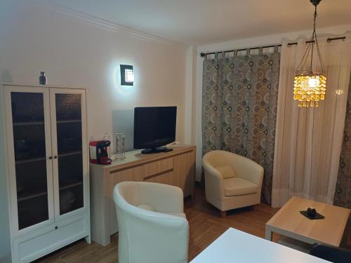 sala de estar con TV y 2 sillas en Apartamento Victor Arico, en El Médano