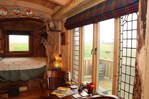 1 dormitorio con 1 cama, escritorio y ventanas en Cushieston’s Shepherd’s Hut en Meikle Wartle