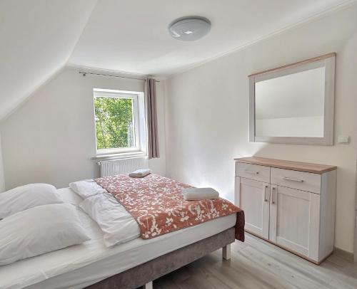 a white bedroom with a bed and a mirror at Apartamenty Golf Dyndeby in Neksø